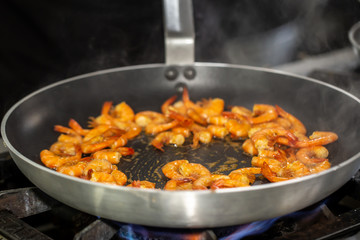 Process of frying shrimp with garlic in olive oil in the black pan. step by step cooking