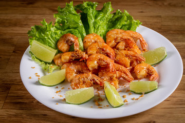 portion of shrimp fried in garlic and oil with lemon on wooden background