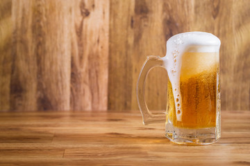 Mug of tasty beer on wooden background