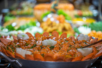 seafood paella on the foreground with defocused restaurant food buffet in the background