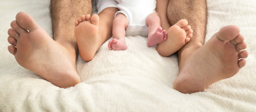 father and children feet in bed in the morning