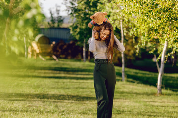 Obraz premium The girl hugs her bear against a background of nature.