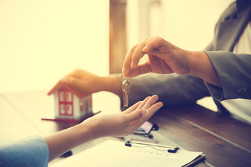 real estate agent gives the keys to the house buyer and signs the contract in the office.