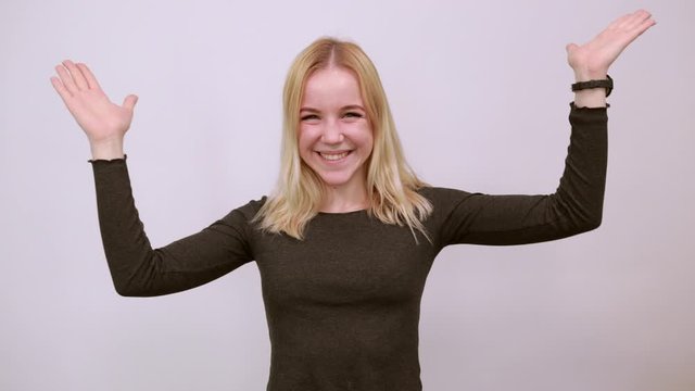 Young Blonde Woman In Black Sweater With Stylish Watch On White Background, Surprised Girl Holds Her Hands Wide, Raised Them Up. The Concept Of Surprise, Shock. Caught A Lady Off Guard