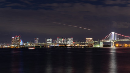 Fototapeta na wymiar 芝浦ふ頭から見たレインボーブリッジとお台場の夜景と飛行機、船の光跡