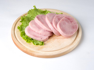 Ham sliced on a blackboard. Next to a leaf of lettuce