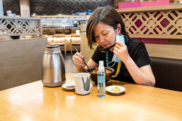 Asian women having meal with facemask and sanitazer, with social distancing