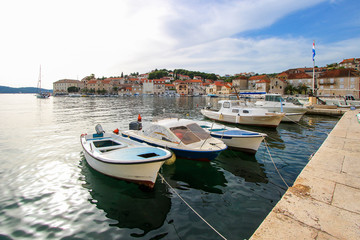 Fototapeta na wymiar Row boats moored at the waterfront of the town of Milna in the island of Brac in Croatia - Small fishing village in the Adriatic Sea