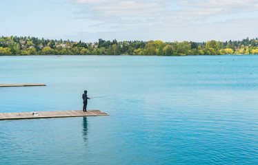 Fototapeta na wymiar a man fihing in the blue lake in the park.