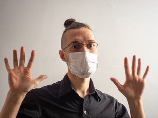 Young Blond Hair Caucasian Male in Black Shirt and Glasses Wearing a Disposable Face Mask for Covid-19, Cought, Flu, Virus, Viral Protection is Showing his two Hands