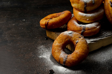 Donuts sprinkled with powdered sugar on dark background