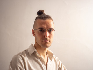 Obraz premium A Young Blond Caucasian Male with Glasses is Looking at the Camera in a White Background