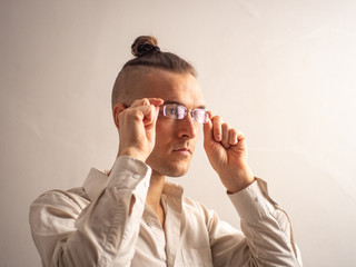 A Young Blond Caucasian Male Puts on his Glasses