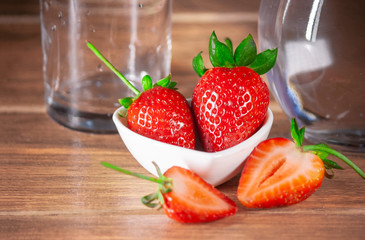 red strawberries whole and sliced ​​half and glass cup and jar