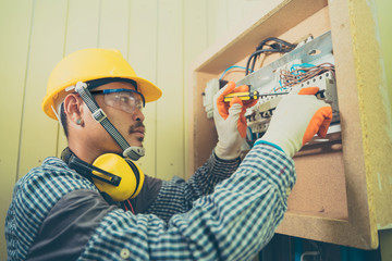 Young repairman fixing electrical,Electrician checking wires in electrical box with pliers in corridor of a residential electrical system.