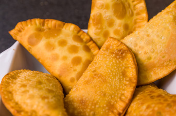 Great photo of Brazilian pastry (pastel), traditional dish of Brazilian cuisine in a dish on a black granite background.
