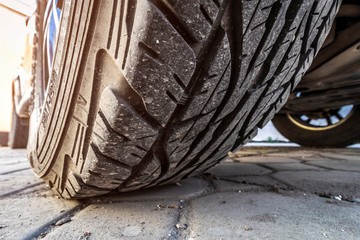 Tread of a wheel of an off-road car standing in the back yard, closeup.