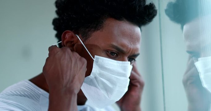 Blck african man removing covid mask looking out pensive