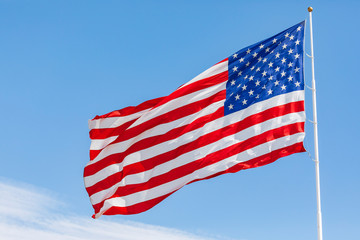 American flag waving in the wind on blue sky, US flag motion close-up, red white blue flag outdoors...