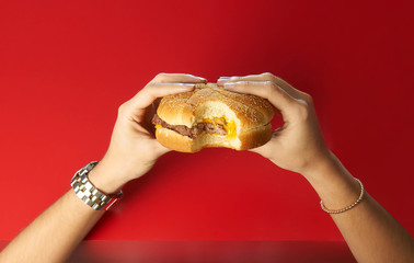 Hands holding Wendy´s burger with a bite on a red table background