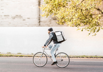 Food delivery courier riding a bike on his way to deliver an order as quick as possible