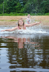 The girl enjoys swimming on the lake in summer. She really likes to splash in the water. Lake, pond, reservoir, water, river, summer, heat, klitsa, weather, warm, child, girl, joy, game.