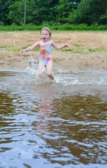 The girl runs into the water to swim.