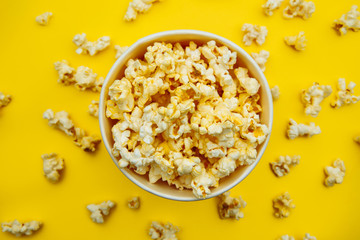 Bowl with popcorn on yellow background. Top view. Entetainement concept.