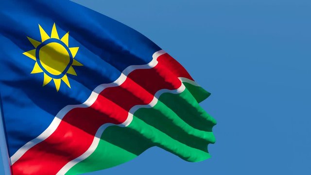 The national flag of Namibia flutters in the wind against a blue sky