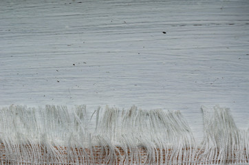 Linen towel with fringe on a white wooden background.