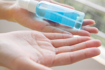 Closeup of cracked hands with alcohol spray bottle. Concept of using alcohol repeatedly during coronavirus pandemic crisis cause dry skin.