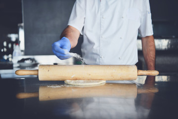 chef  with protective coronavirus face mask preparing pizza
