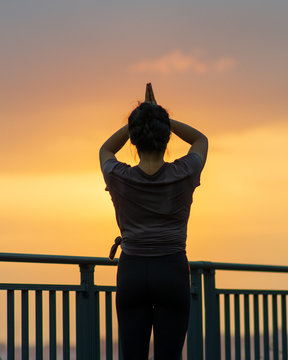 Young Women Doing Yoga Meditation On A Rooftop Garden In An Apartment During The Lockdown During Sunset