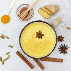 Turmeric latte top view. Golden milk in cup with star anise and ingredients around. Menu, recipe of...