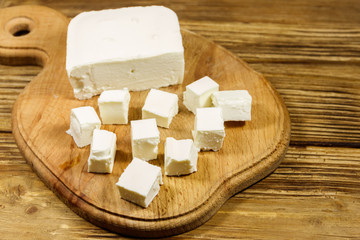 Feta cheese on cutting board on a wooden table