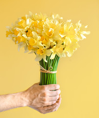 Background male hands with a bouquet of flowers .