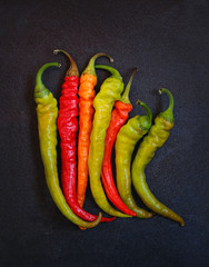 Red, yellow and green hot chilli pepper on black grunge background. spice, ingredient for kitchen.