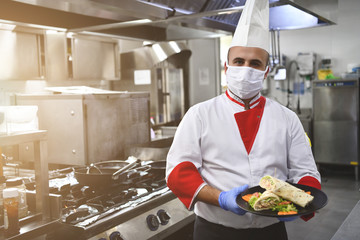 chef cook wearing face protective medical mask for protection from coronavirus