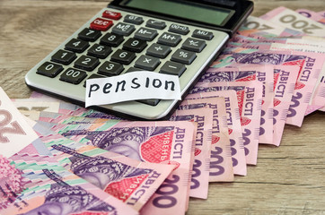Pension concept. Hryvnia with a calculator and the word "pension".