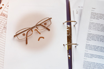 Glasses for visual acuity as part of a smiley unhappy with paperwork over printed documents. Boring...