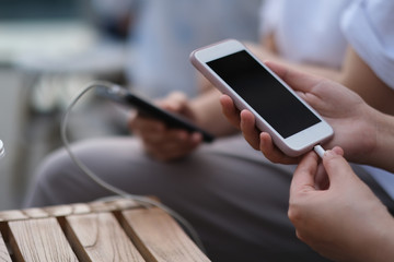 close up people sharing portable battery to charge phone. blur background