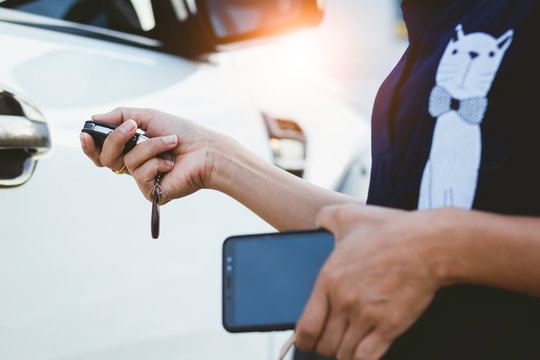 Woman Unlocking The Car And Holding Smartphone For Background.