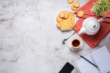 Afternoon tea set with bread, crackers, and a mobile phone and a notebook beside, with copy space, top view.