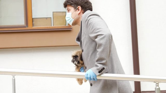 guy with damaged leg walks to hospital holding small dog in hand with sterile glove slow motion. Concept coronavirus