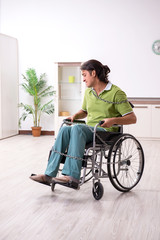 Young male invalid in wheel-chair suffering at home