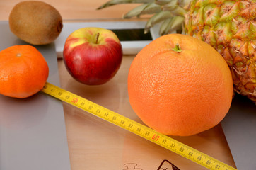 different fruits on the scales diet concept with measuring tape