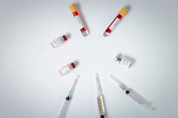 Top view of vaccine, blood samples in tubes and syringes on work table in a medical examination lab.