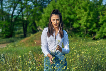 Portrait of a young girl on a country walk in the countryside . A girl in jeans and a light shirt on a walk