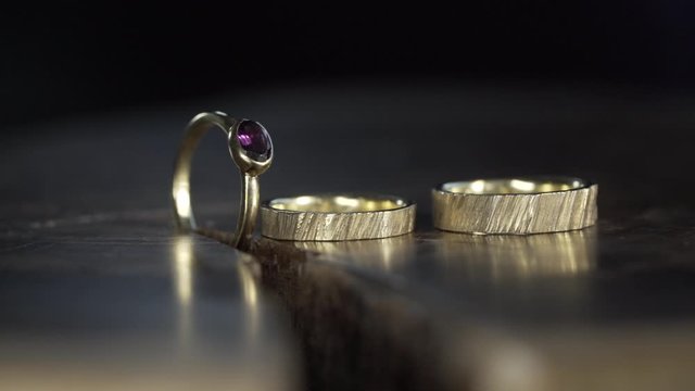 Goldene Eheringe mit Verlobungsring in Zeitlupe