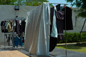 Many pieces of clothes hanging on the stainless rack for drying with the sunlight.